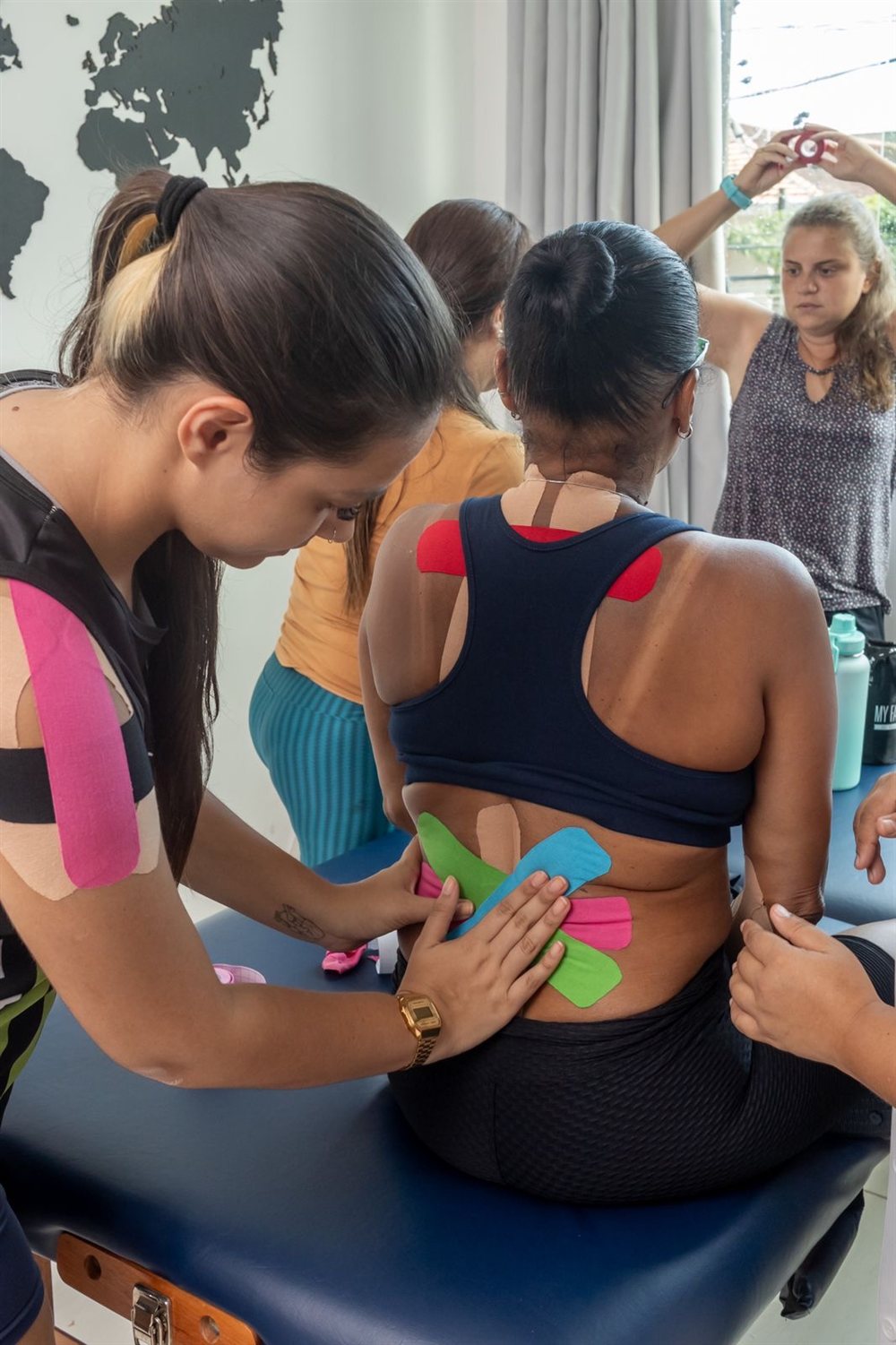 Aluna aplicando kinesiotape na lombar de uma colega durante o curso
